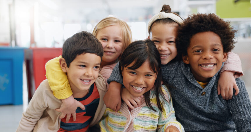 Students in classroom smile together.
