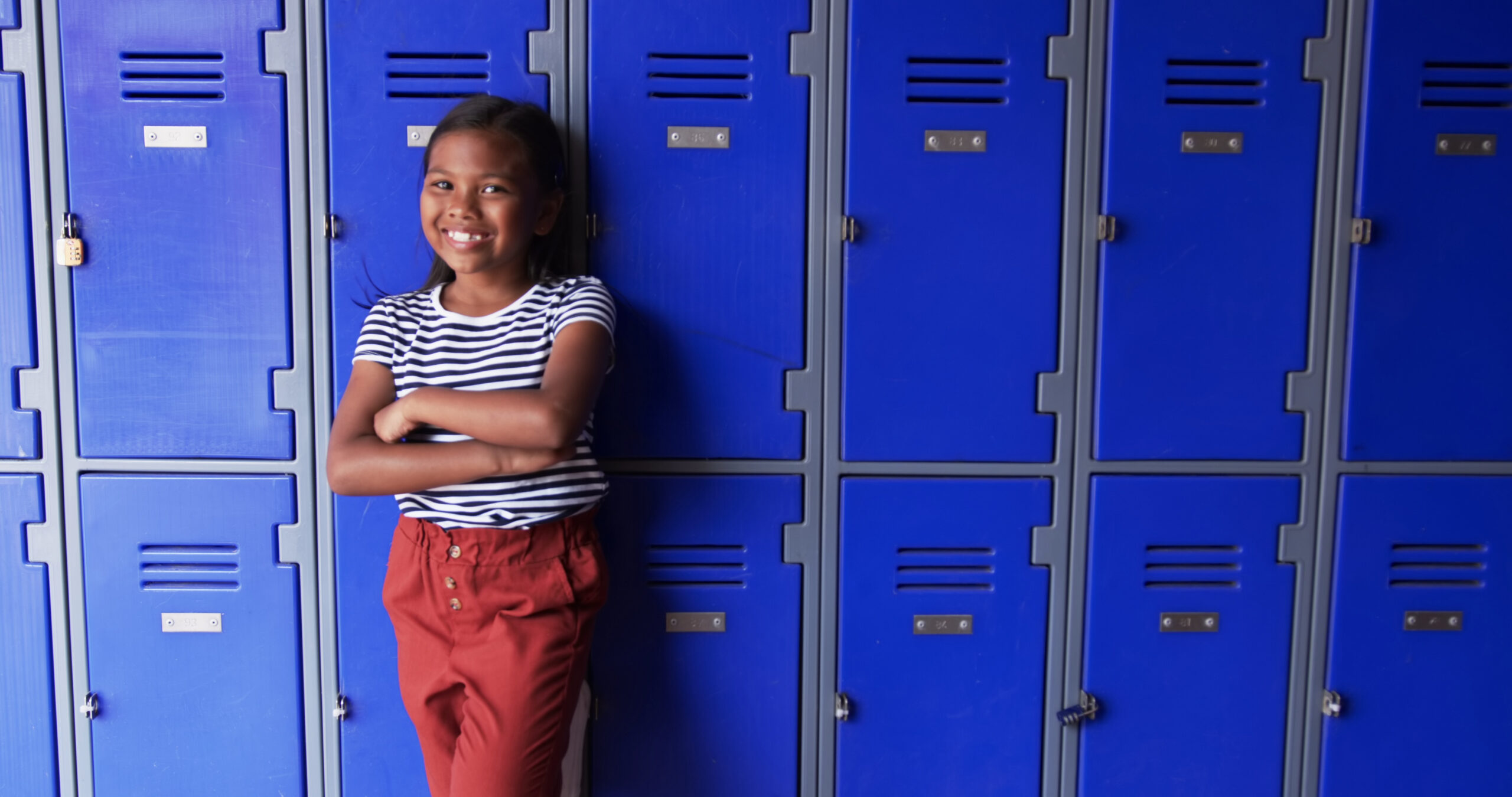 Young student leans against lockers.